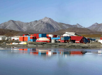 The buildings housing the mill and other Red Dog facilities reflect off a pond.