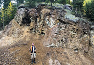 Palladium One VP Exploration Neil Pettigrew standing below rocky outcrop.