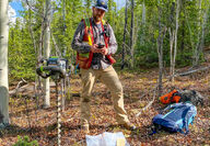 Geologist with handheld drill collects soil sample at copper project in Alaska.