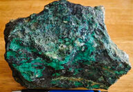 A roughly eight-inch rock sample stained green from copper oxides.