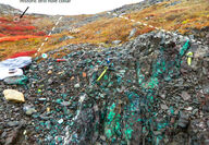 A rock outcrop stained green with copper mineralization.