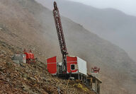 Clouds encompass a drill testing for copper and gold from a mountainside perch.