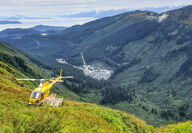 Looking down a mountain toward a helicopter and Kensington Mine site.