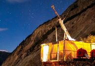 Mineral exploration drill rig glowing yellow from lights shining through canvas.