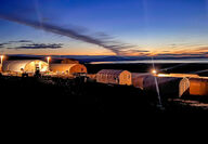 A colorful sunset backdrops a graphite exploration camp in Alaska.