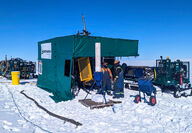 A drill inside a green enclosure test for copper below the snow in Nunavut.