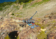 A drill tests for gold from atop heavily mineralized outcropping rock in B.C.