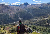 Yukon Metals’ geologist standing atop of ridge overlooking a valley.