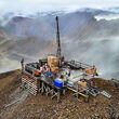 A drill tests for gold from atop a ridge in the Alaska Range mountains.