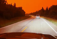 Photo taken through car windshield by evacuee in line of cars under red sky.