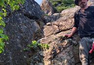 North Arrow geologist stands next to spodumene outcrop.