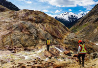 Geologists in safety gear traverse heavily mineralized rocks.