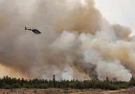 Crews in helicopters battle a forest fire near Yellowknife, NWT.