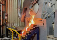 Molten gold poured from a kiln cascades down a stairstep of bar molds.