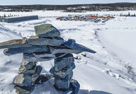 A large mineral exploration camp lies beyond an inuksuk in northern Canada.