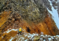 A geologist stands on a ridge next to the orange-stained Stoney Vein.