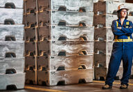 Female worker stands in front of zinc billets produced at Trail Operations.