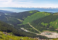 View over building in a valley towards a bay and snowcapped mountains.