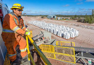 A mine worker in high visibility coveralls and hard hat monitors operations.