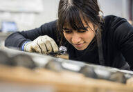 Female technician takes closer look at gold in core with a geologist loupe.