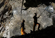 Two workers remove loose rocks from an underground mine at Kensington.