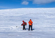 Workers lay out geophysical sensors on snow covered treeless area.