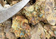 Hunk of gold-mineralized rock next to rock pick hammer.